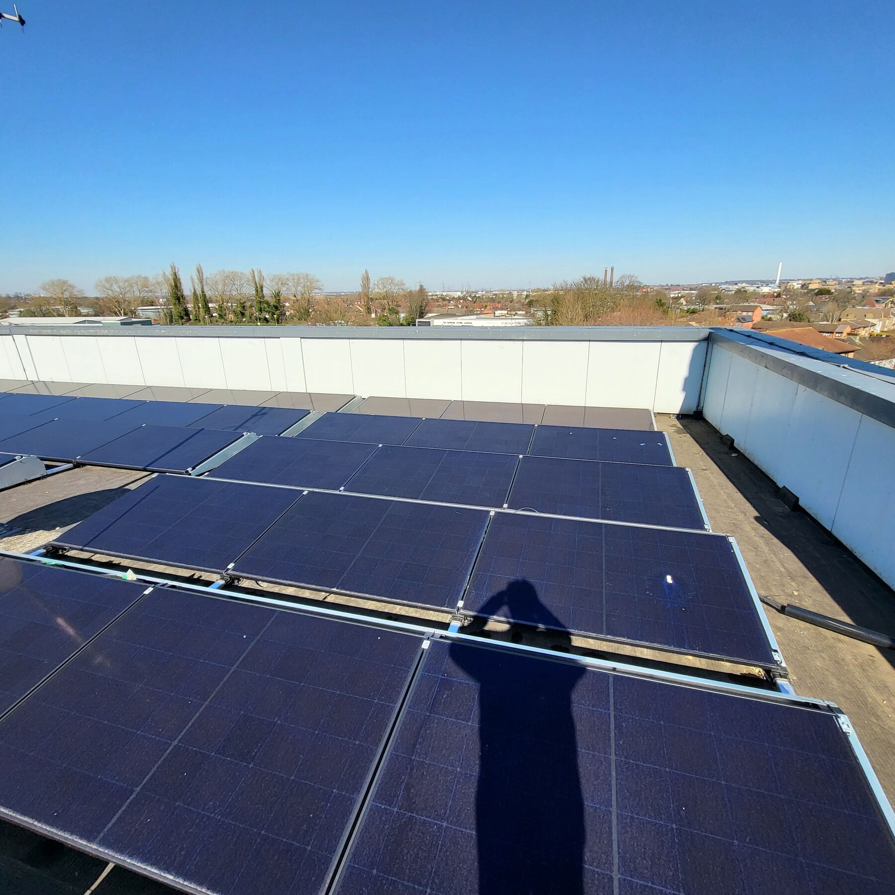 Photovoltaic panel rows and rooflights on a commercial roof under clear sky