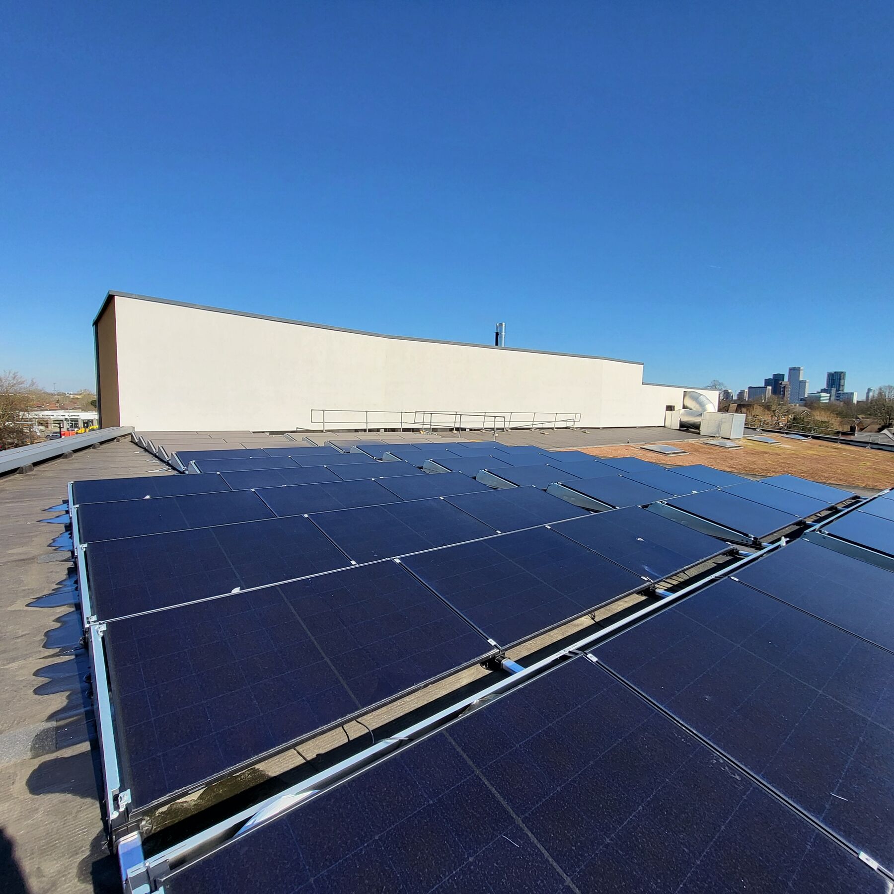 Rows of photovoltaic panels mounted on a large flat commercial roof