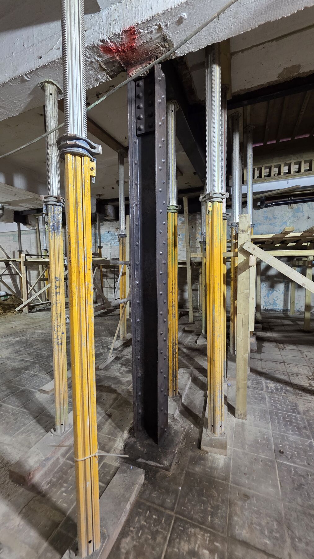 Adjustable steel props supporting a beam during structural alterations