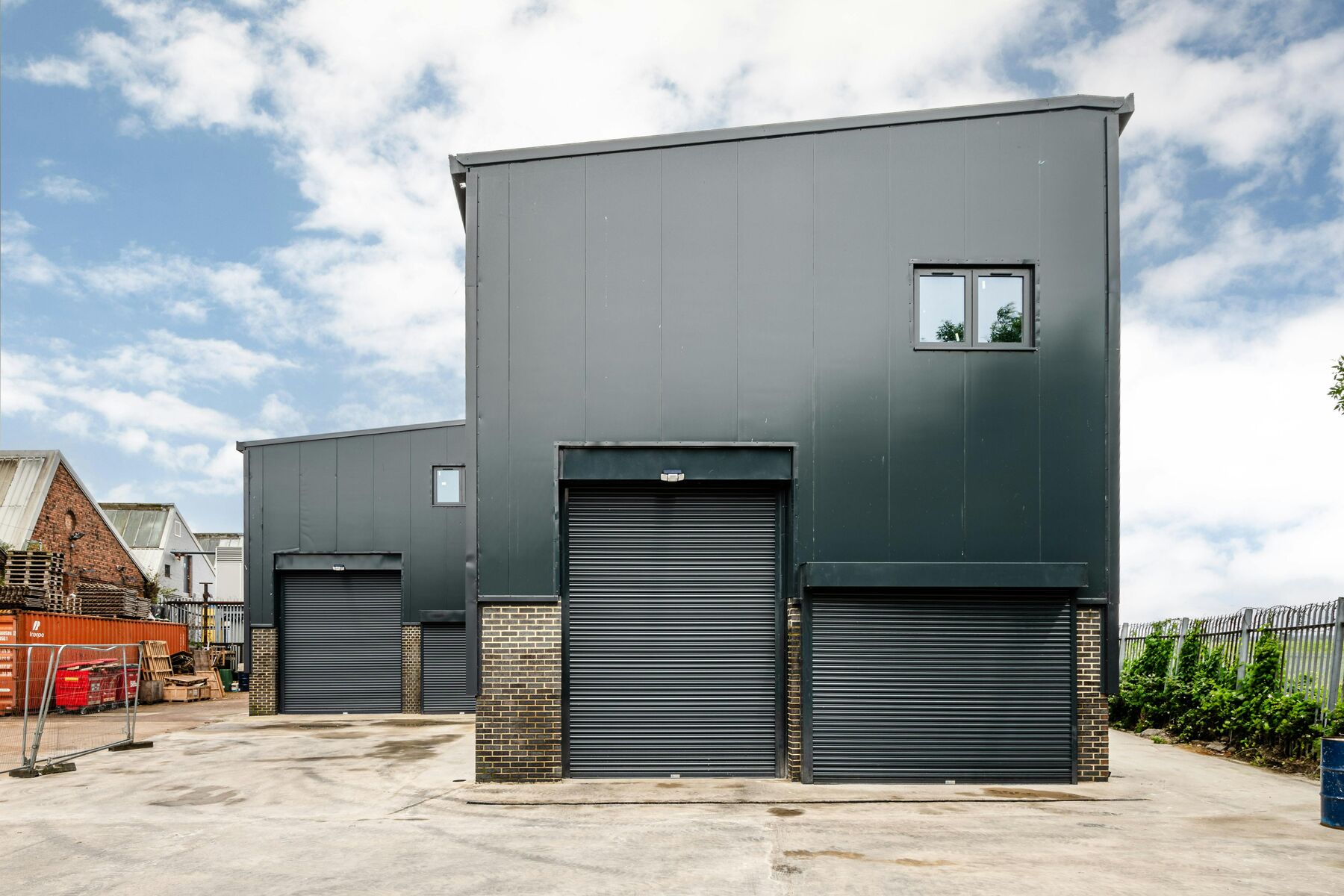 Completed steel-framed industrial unit with roller shutter doors at Uplands Business Park
